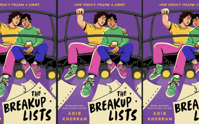 Cover of the book shows two young men sitting up above the lights on a catwalk in a theater. One has his arm around the other and their heads are leaning onto each other. There are three copies of it next to each other.